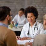 Black female general practitioner having consultations with a couple at clinic.